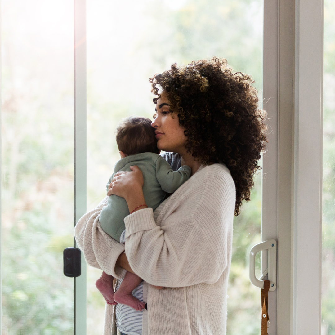Mother holding baby with a neutral look on her face.