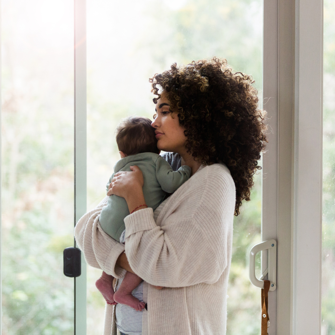 Mother holding baby with a neutral look on her face. 